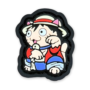 以下が含まれることがあります： 赤と白の帽子と青いシャツを着た猫の白黒の漫画パッチ。猫は足を組んで座っており、顔に大きな笑顔をしています。