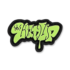 May include: A lime green and black shoe charm with the word "RIPNDIP" in a graffiti-style font. The text is outlined in black and has a dripping effect on the bottom. The charm is a shoe accessory.