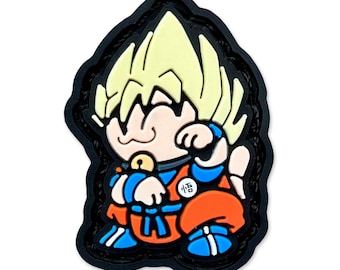 May include: A colorful cartoon character patch featuring a figure with spiky blonde hair, wearing an orange and blue outfit. The patch has a black border and includes a small Japanese character.