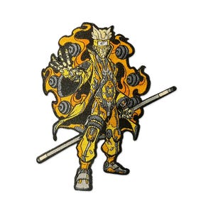 May include: Embroidered patch showing an anime-style character in yellow, black, and grey. The character has a flowing cape, a staff, and detailed armour. The patch features a flame-like design around the character.