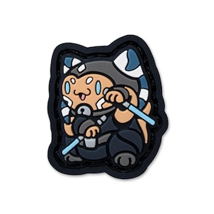 Könnte beinhalten: Ein Cartoon-Patch mit einem katzenartigen Charakter in Kriegerkluft, der zwei blaue Lichtschwerter hält. Der Charakter hat hellbraunes Fell, blaue und weiße Markierungen und ist vor einem schwarzen Hintergrund platziert.