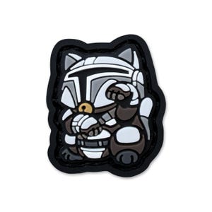 May include: A patch featuring a cat-shaped character in Mandalorian armor. The design incorporates shades of gray, white, and brown, with a black border. The cat is in a seated position, with one paw raised. The patch is a unique blend of pop culture and feline charm.