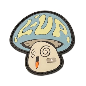 May include: A mushroom-shaped patch with a light blue cap and a cream-coloured stem. The cap features the word "ZUP" in yellow. The mushroom has a surprised expression with spiral eyes, an open mouth, and a bandage. The patch is outlined in black.