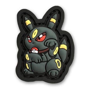 Puede incluir: Parche de personaje Pokemon negro y amarillo con ojos rojos. El personaje está sentado con los brazos cruzados y tiene una Poké Ball roja en el pecho.