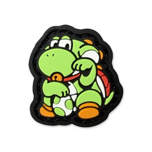Puede incluir: Parche de personaje de dibujos animados verde con detalles en naranja, blanco y rojo, y un borde negro. El personaje sostiene un huevo blanco y verde moteado. El parche es probablemente para ropa o accesorios.
