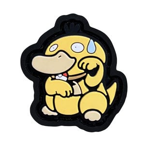 Può includere: Un personaggio dei cartoni animati giallo con un grande becco, piccoli occhi e una goccia di sudore, su sfondo nero. Il personaggio è seduto, con le braccia incrociate. Il design è un ciondolo in stile 3D.