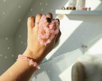 May include: A pink rose quartz crystal bracelet and necklace set. The bracelet and necklace are made of small, irregular shaped rose quartz crystals.