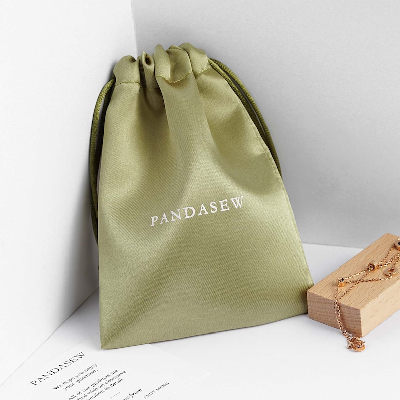 green satin bag with green smooth satin string, white logo on green satin bag