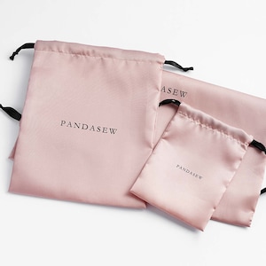 pink color satin bag with black satin ribbon and black logo, custom dust bag