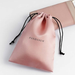 pink color satin bag with black smooth satin string, black logo on pink satin
