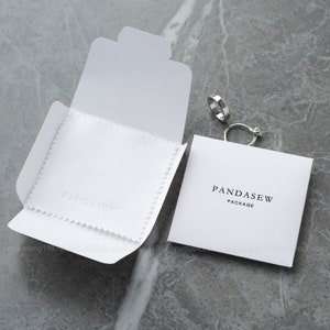 white polishing cloth was put on white paper case. Both of them are deboosed logo.