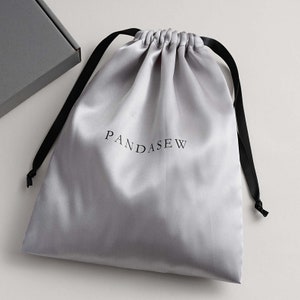 light grey color satin, silver shade satin bag with black smooth satin ribbon and black logo