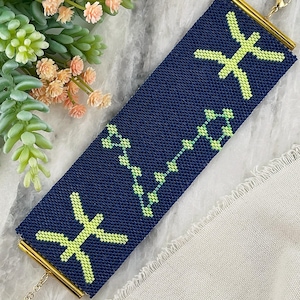Op de afbeelding: Een rechthoekige kralenarmband met een donkerblauwe achtergrond, voorzien van een fel limoengroen Vissen-sterrenbeeldteken aan beide uiteinden en een centraal limoengroen sterrenpatroon. De armband heeft goudkleurige metalen eindstukken en een sluiting.