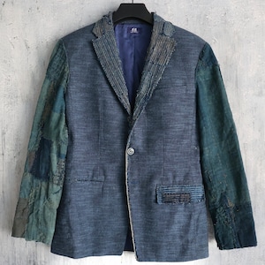May include: A blue blazer with a patchwork design on the sleeves. The blazer has a single button closure and a pocket on the left side.