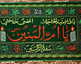 May include: A green textile featuring Arabic calligraphy in red, yellow, and white. The central text reads "Ya Umm al-Banin." The border includes more script and decorative elements in various colours. Two candle illustrations are on either side of the central text.