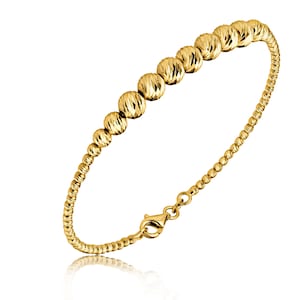 May include: A gold bracelet with a beaded design. The beads are round and have a textured surface. The bracelet has a clasp closure.