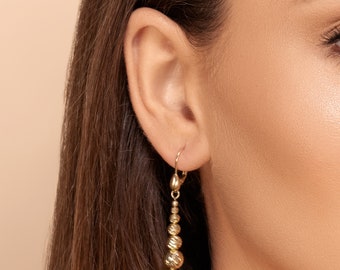 Petra earrings - 14k graduated beaded dangle earrings in solid yellow gold displaying shiny diamond cut ball beads