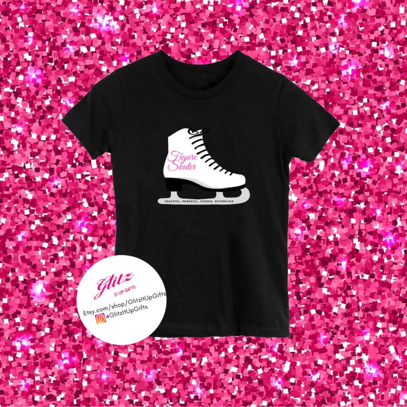 May include: Black t-shirt with a white figure skate graphic and the text "Figure Skater" in pink. The text "GRACIOUS, POWERFUL, STRONG, DETERMINED" is printed in small white letters below the skate. The text "Glitzz It Up Gifts" is printed on a white circle in the bottom left corner of the shirt.