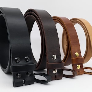 May include: Four leather belts in varying shades of black, brown, and tan are displayed. Each belt is rolled and features a buckle or attachment hardware. The belts are made of smooth leather and are suitable for various uses.