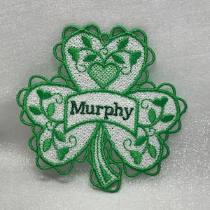 May include: Green embroidered shamrock with a white center and a banner that reads "Murphy".