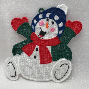 May include: A white snowman with a red scarf, green jacket, and blue hat with white stripes. The snowman has black eyes, a carrot nose, and a red mouth. The snowman is holding out its arms and has a happy expression.