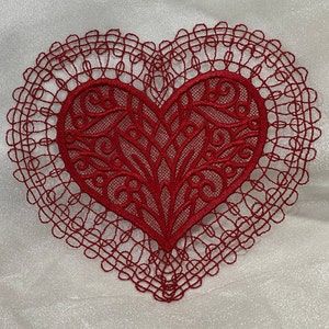 May include: A red lace heart-shaped applique with intricate designs. The lace is delicate and has a vintage feel.