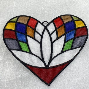 May include: A heart-shaped embroidered patch with a stained glass design. The design features a white flower with red, yellow, blue, green, and brown geometric shapes.