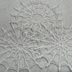 May include: Three white lace doilies in the shape of a spider web.