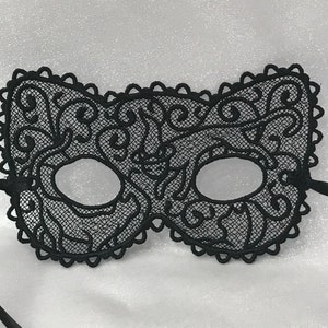 May include: A black lace masquerade mask with intricate floral designs. The mask has two eye holes and a ribbon tie.