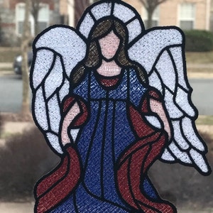 May include: A blue and red embroidered angel with white wings, hanging from a suction cup.