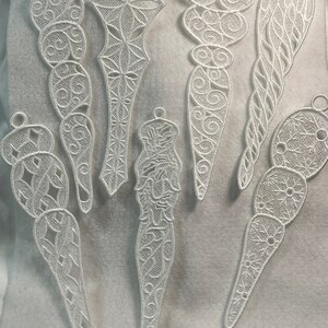 May include: Seven white lace ornaments with intricate designs. The ornaments are all different shapes and sizes, and they are all made of a delicate, white lace.
