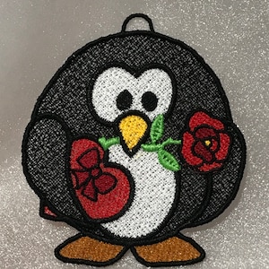 May include: Embroidered penguin holding a red heart and a single red rose with green stem and leaves. The penguin is black and white with a yellow beak and brown feet.