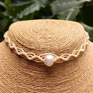 Peut inclure: Un collier ras de cou en macramé blanc avec un seul accent de perle blanche.
