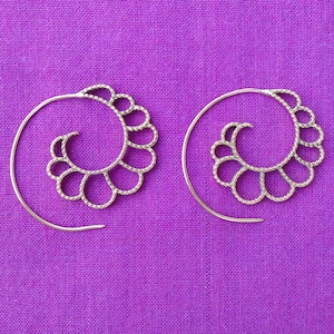 Puede incluir: Un par de pendientes de aro de plata con un diseño en espiral. Los pendientes están hechos de metal fino y tienen un aspecto delicado y femenino.