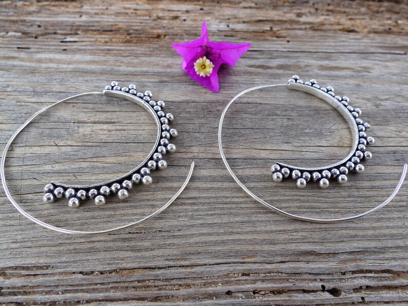 May include: A pair of silver hoop earrings with a beaded design. The earrings are large and have a circular shape.