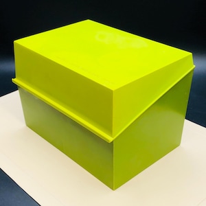 Puede incluir: Una caja rectangular verde lima con tapa a juego. La caja tiene un acabado ligeramente brillante y un diseño geométrico simple. La tapa se asienta perfectamente en la parte superior, creando un aspecto limpio y moderno. La caja es probablemente para almacenamiento.
