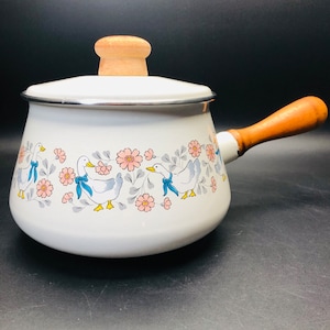 May include: White enamel saucepan with a wooden handle and a floral design featuring pink flowers and blue ducks.