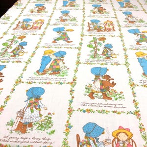 May include: White fabric with a repeating pattern of children in bonnets and floral borders. The illustrations feature children in various activities, with text snippets. The color palette includes blue, yellow, green, and brown.