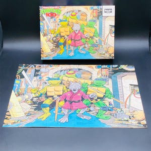 May include: A vintage 100-piece jigsaw puzzle featuring the Teenage Mutant Ninja Turtles. The puzzle and box art show the turtles and Splinter in a colorful action scene. The box has the text "Turtles 100" and the logo of the puzzle maker.