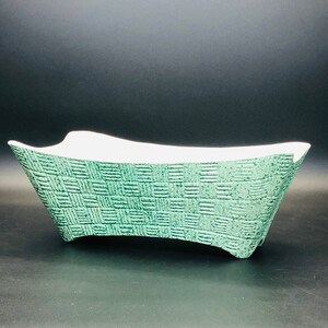Peut inclure: Un bol rectangulaire en céramique avec un extérieur texturé présentant un motif de vannerie vert et un intérieur blanc lisse. Le récipient possède des côtés évasés et une base incurvée, offrant un contraste marqué entre la surface extérieure verte mate et la finition blanche propre du bassin intérieur.