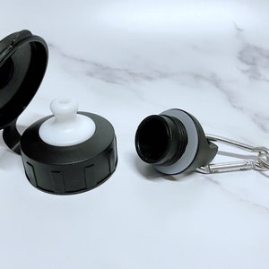 May include: Two black plastic water bottle caps with a white spout and a silver carabiner clip.