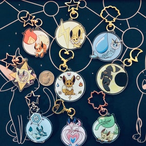 Puede incluir: Un conjunto de diez llaveros coloridos con diferentes personajes de Pokémon. Cada llavero está hecho de acrílico transparente y presenta un personaje de Pokémon diferente con un anillo de metal dorado y un amuleto en forma de estrella.