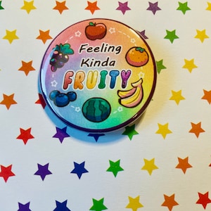 May include: A rainbow-colored button with the text "Feeling Kinda Fruity" and cartoon images of various fruits, including an apple, grapes, an orange, blueberries, a watermelon, and bananas.