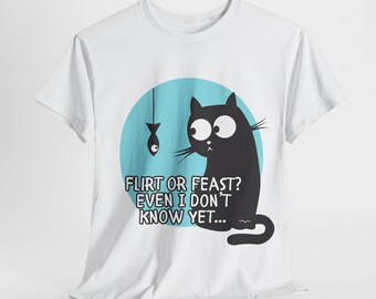 May include: White t-shirt featuring a black cat with large eyes, sitting and looking at a fish on a string. The cat is set against a light blue circle. Text on the shirt reads, "FLIRT OR FEAST? EVEN I DON'T KNOW YET..."