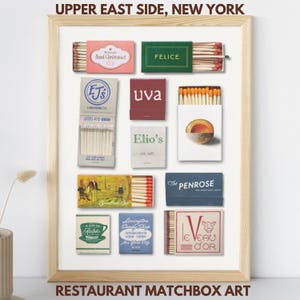 Könnte beinhalten: Ein gerahmter Druck mit Restaurant-Streichholzschachtel-Kunst aus der Upper East Side, New York. Das Kunstwerk zeigt verschiedene Streichholzschachteln mit unterschiedlichen Designs und Restaurantnamen, darunter "Sant Ambroeus" und "Felice". Der Text "Restaurant Matchbox Art" befindet sich unten.