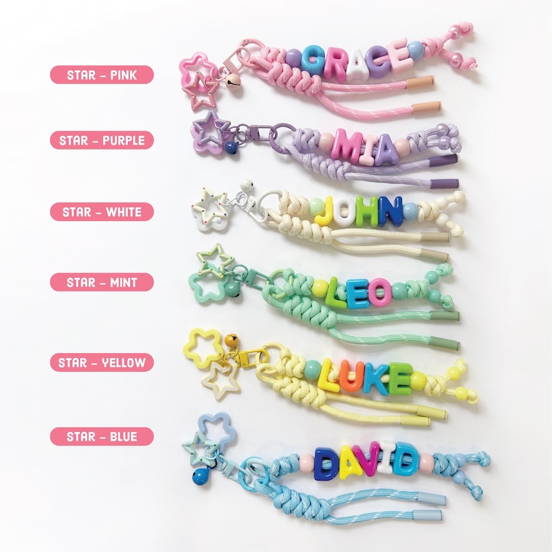 Peut inclure: Une collection de porte-cl&eacute;s personnalis&eacute;s avec des noms &eacute;pel&eacute;s en perles de lettres color&eacute;es. Chaque porte-cl&eacute;s comprend un charm en forme d'&eacute;toile et un cordon tress&eacute; de diff&eacute;rentes couleurs, dont rose, violet, blanc, menthe, jaune et bleu. Les noms incluent GRACE, MIA, JOHN, LEO, LUKE et DAVID.