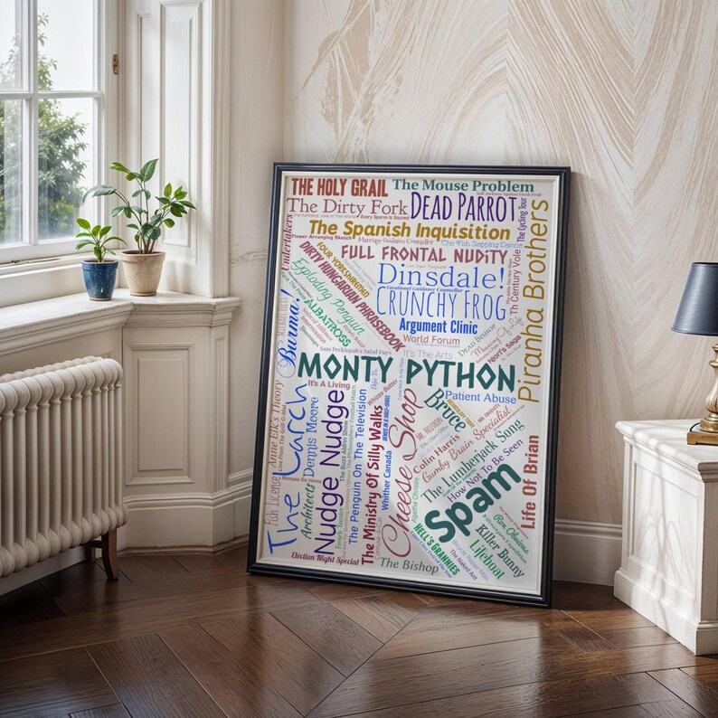 May include: A framed poster with a black border, displaying a word cloud of Monty Python-related phrases. The words, in various colours and fonts, are set against a white background. The poster is displayed in a room with a window and potted plants.