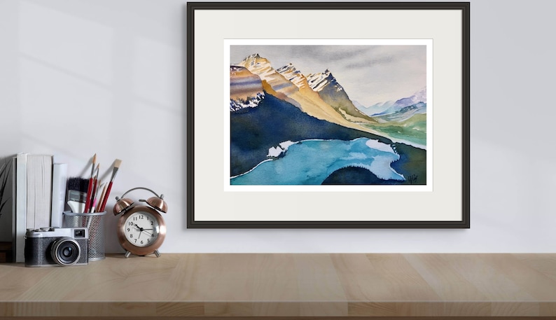 Pode incluir: Uma pintura a aquarela emoldurada que retrata uma cordilheira com um lago em primeiro plano. As montanhas s&atilde;o uma mistura de marrom, amarelo e branco, com neve nos picos. O lago &eacute; de um azul vibrante, com algumas pequenas ilhas. O c&eacute;u &eacute; cinza claro, com algumas nuvens.
