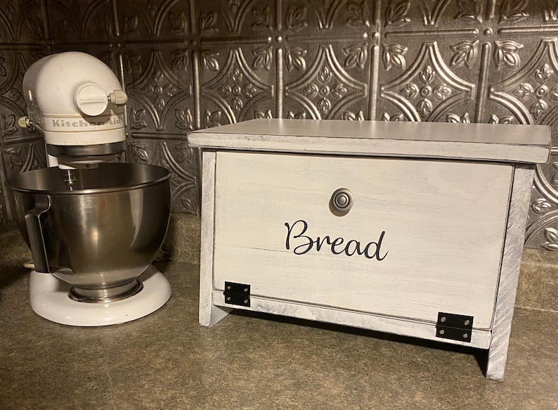 Farmhouse Kitchen Counter Top Handmade Bread Box-Wooden Bread Box-wooden bin - Produce Bin. May also include: White wooden bread box with a silver knob and the word 'Bread' written in black cursive on the front. The bread box is sitting on a countertop next to a white stand mixer with a silver bowl.