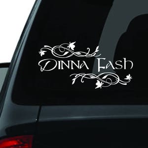 May include: White vinyl decal with the text "Dinna Fash" in a decorative script font with floral accents. The decal is applied to the rear window of a black car.